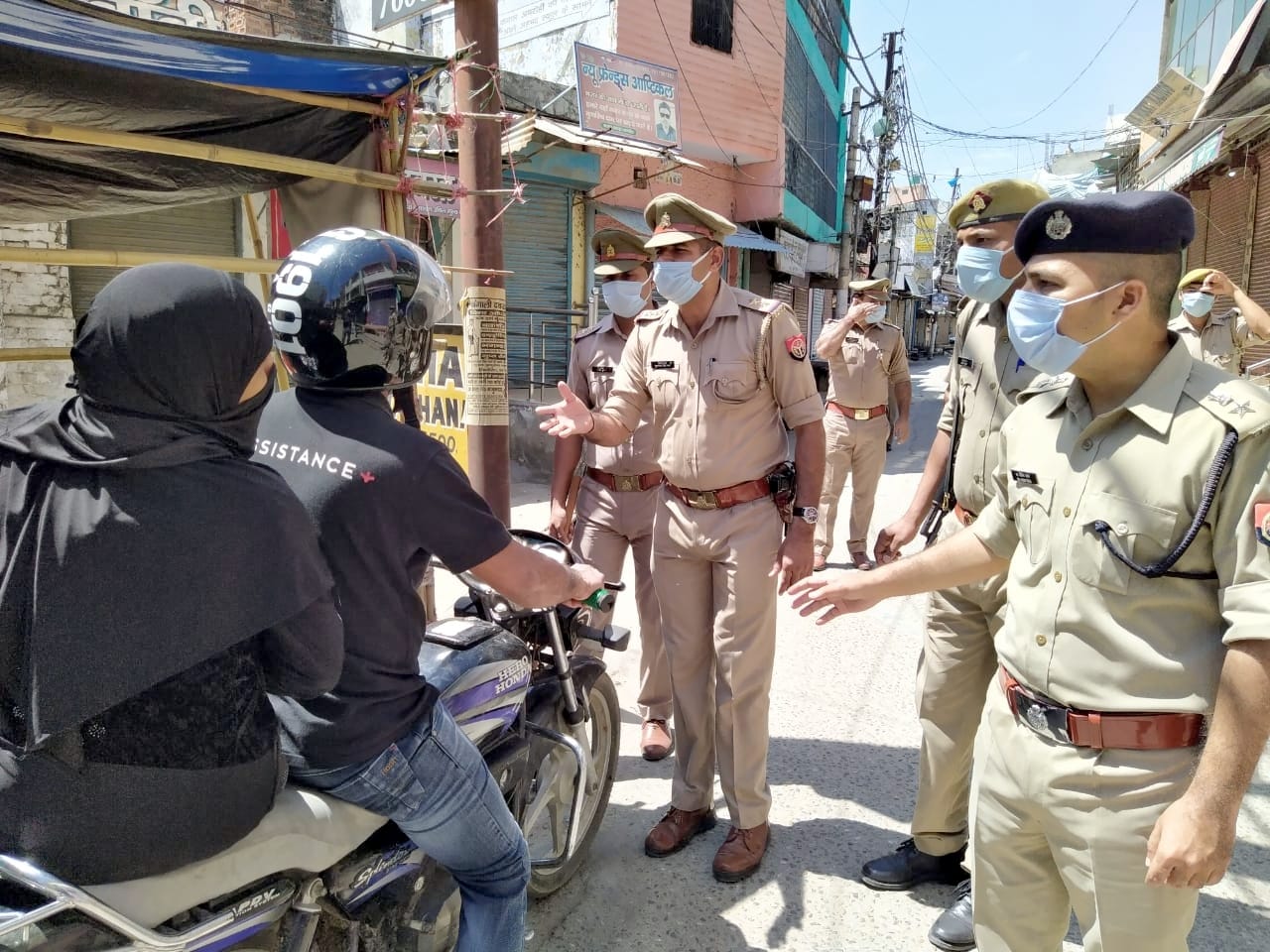 औरोहा में पैदल गश्त के दौरान बाइक सवारों को रोकर घर से निकलने का कारण पूछते एसपी व अन्य पुलिस कर्म?