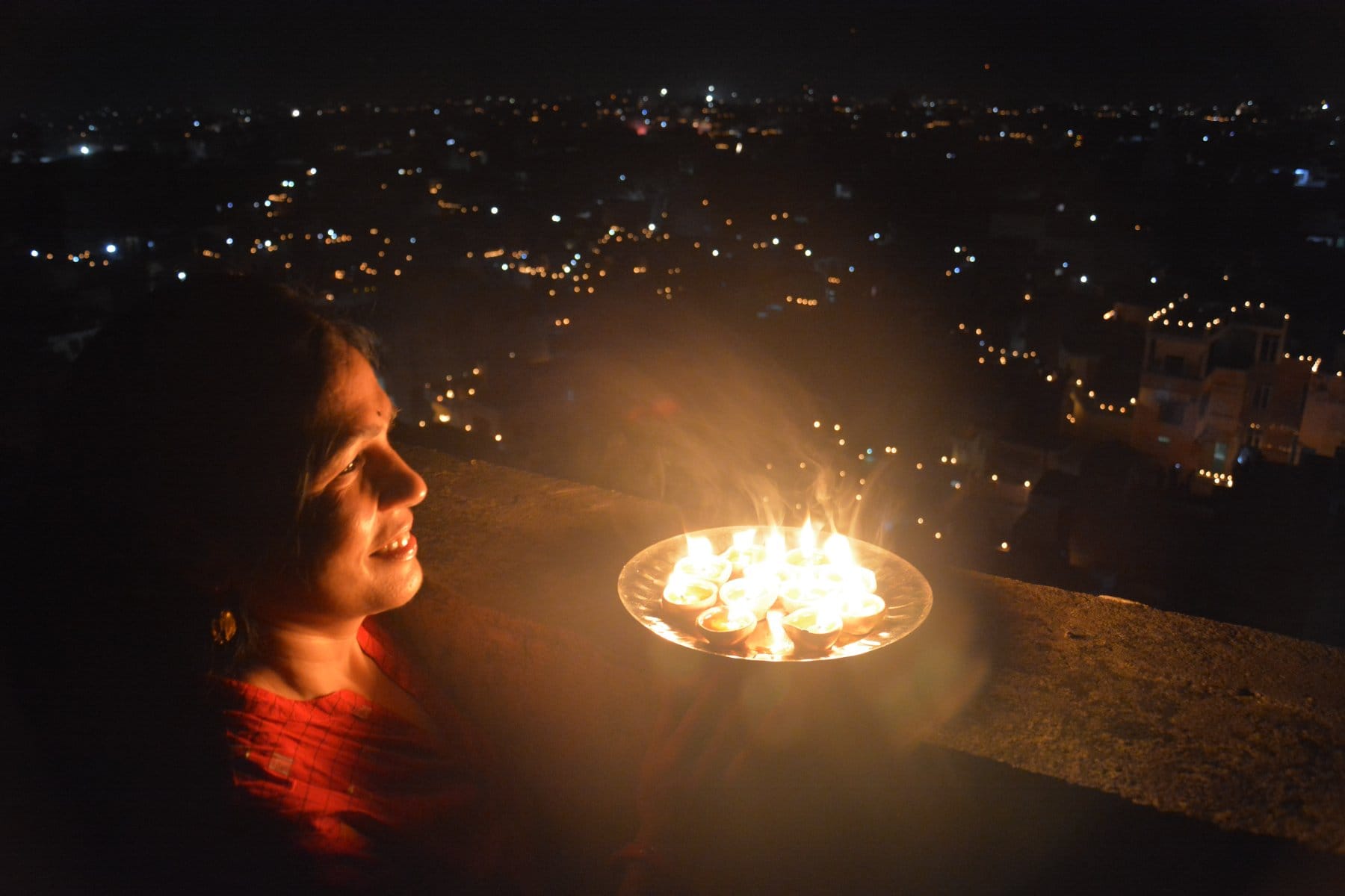 नगर में नौ दीपक जलाकर महामारी का अंधकार मिटाने का संकल्प करती महिला । नगर में नौ दीपक जलाकर महामारी का अंधकार मिटाने का संकल्प करती महिला ।