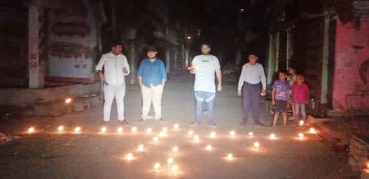 शहर में मार्ग पर दीपक जलाते नागरिक।