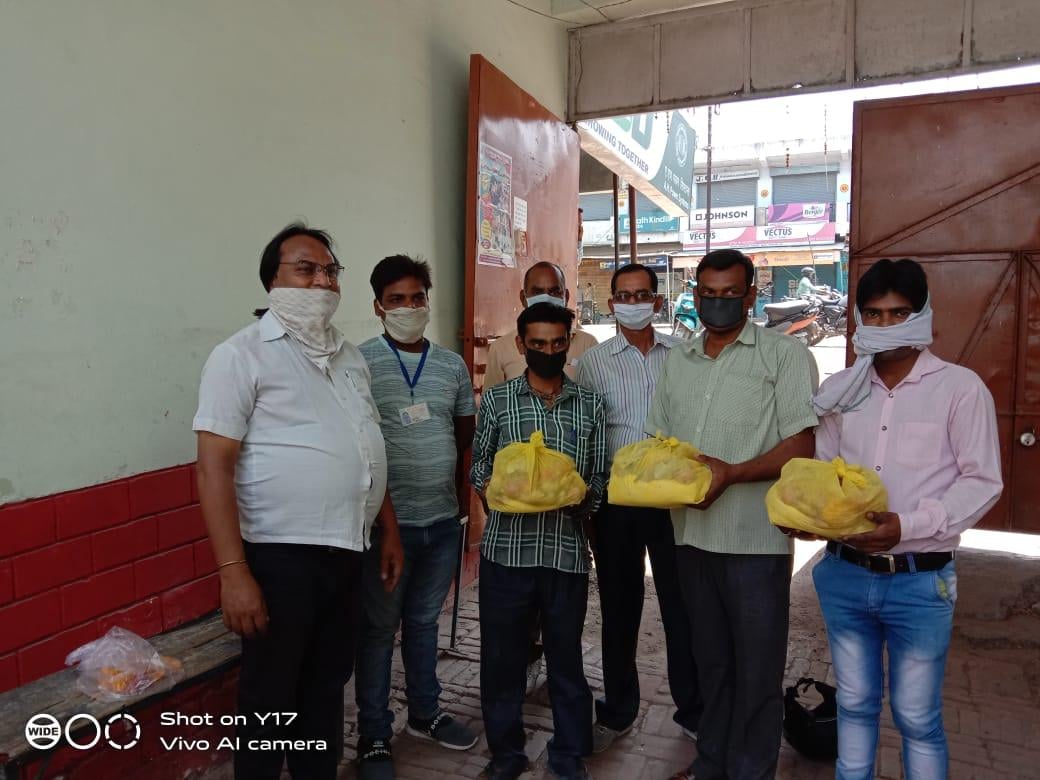 संस्कार ग्रामोत्थान संस्था के पदाधिकारी कर्मयोगियों को पैकेट थमाते।