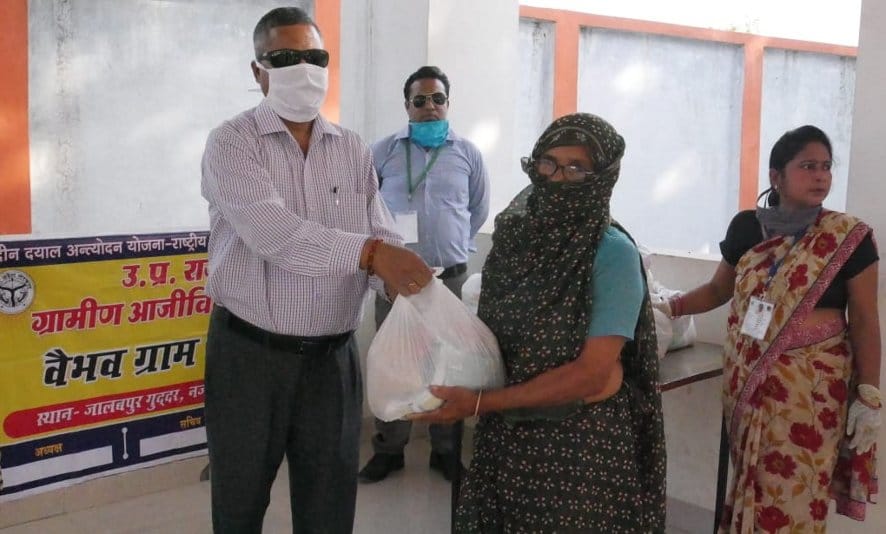 नजीबाबाद के जालबपुर गूदड़ में राशन किट देते उपायुक्त स्वत: रोजगार ज्ञान सिंह।