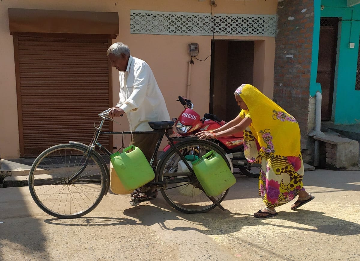 साइकिल पर पानी ढोते लोग साइकिल पर पानी ढोते लोग