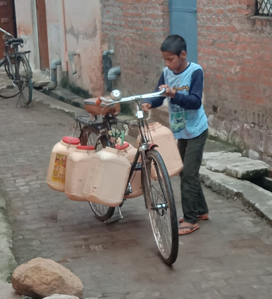 साइकिल से पानी ढोता बच्चा साइकिल से पानी ढोता बच्चा