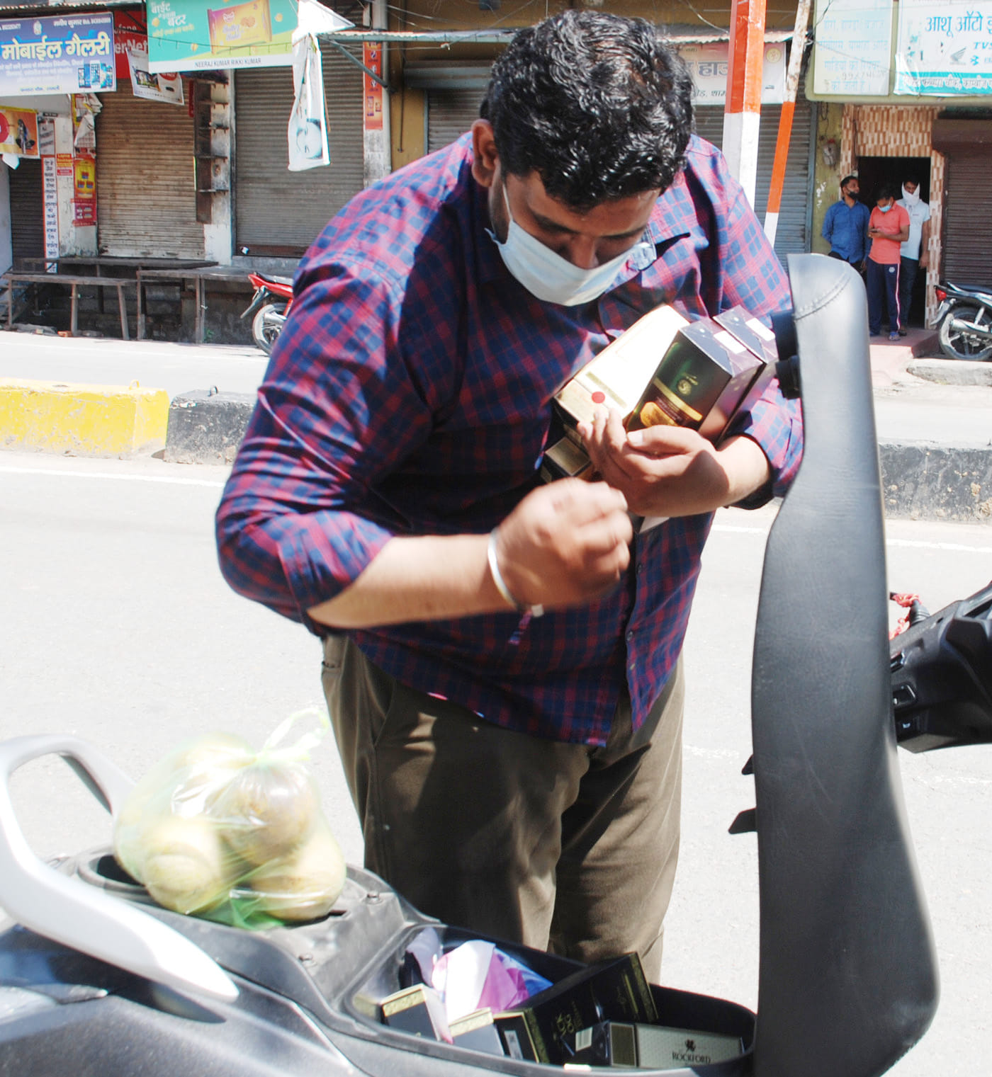 शामली में ठेके से शराब की बोतलें लेकर स्कूटी रखता युवक। शामली में ठेके से शराब की बोतलें लेकर स्कूटी रखता युवक।