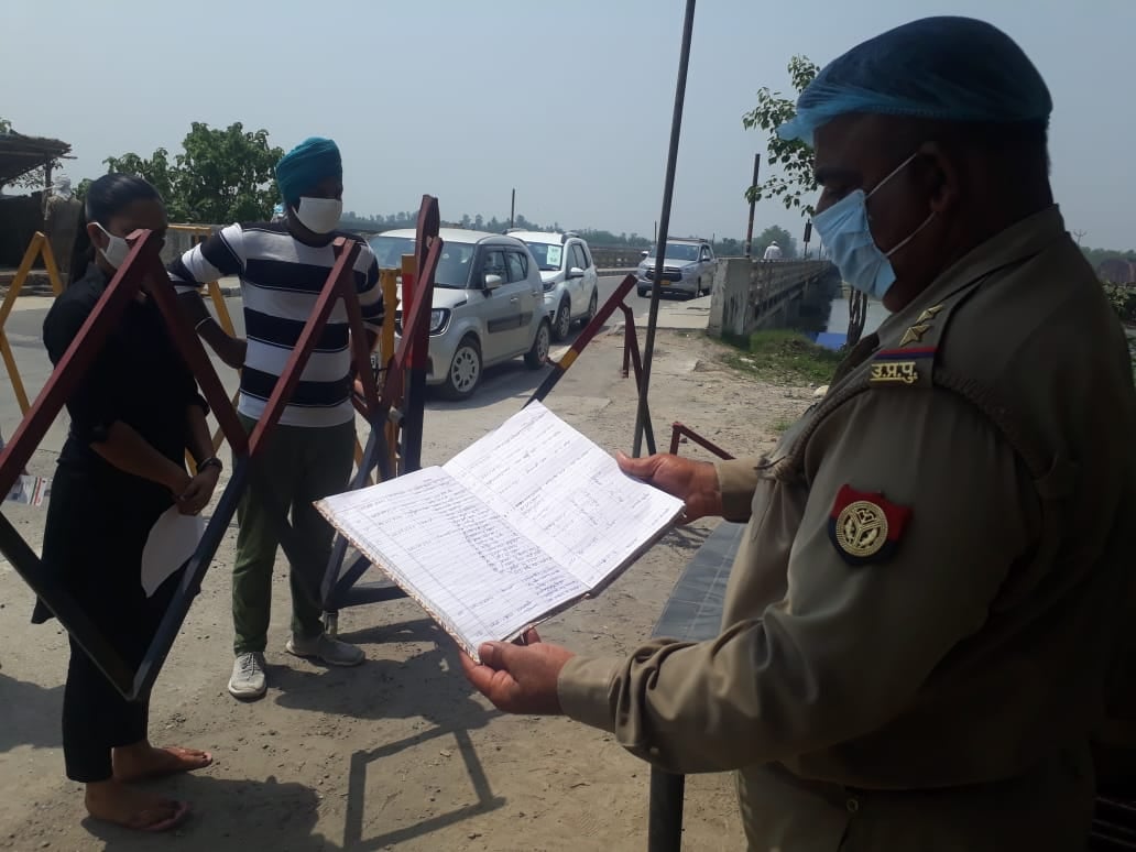 शाहजहांपुर पुलिस चौकी पर आने वालो का ब्यौरा चैक करते पुलिसकर्मी