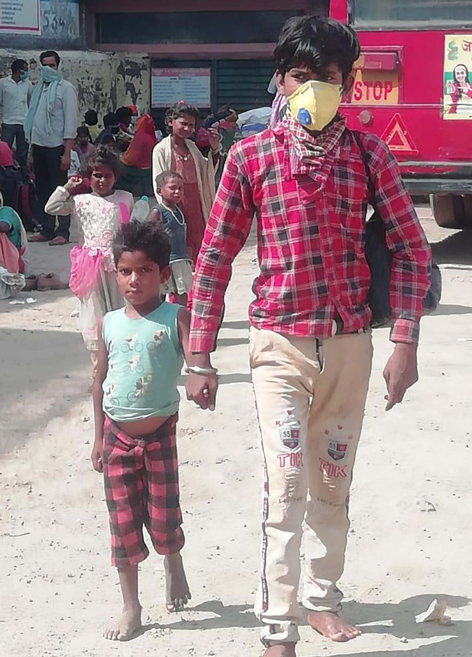 नंगे पैर छोटे भाई का हाथ पकडकर चलता किशोर। नंगे पैर छोटे भाई का हाथ पकडकर चलता किशोर।