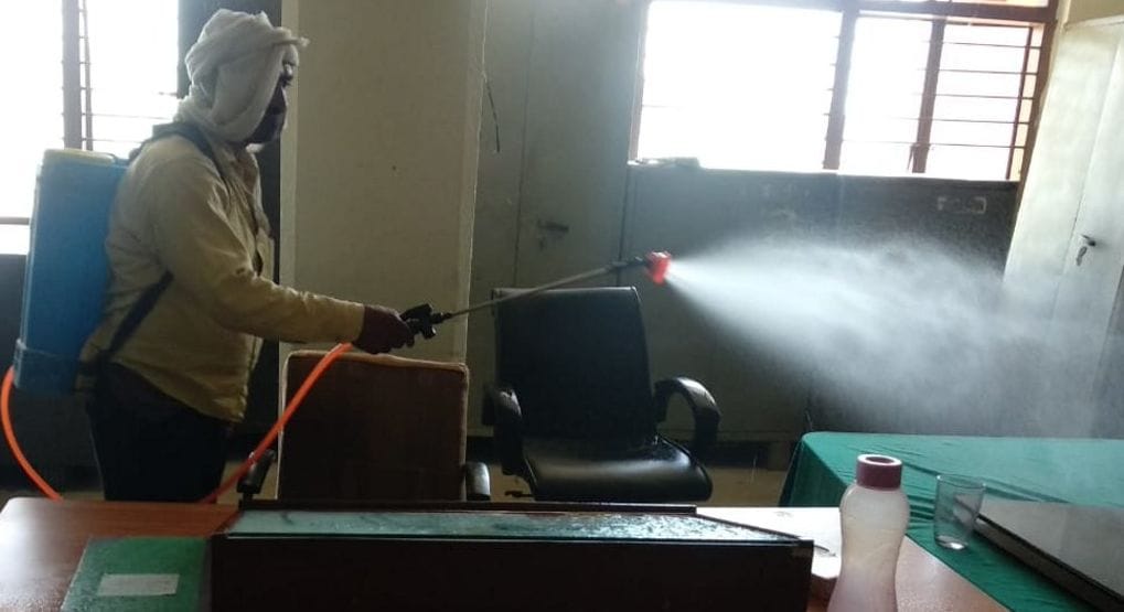 विकास भवन के कार्यालय में सैनिटाइजर का छिड़काव करता कर्मचारी।