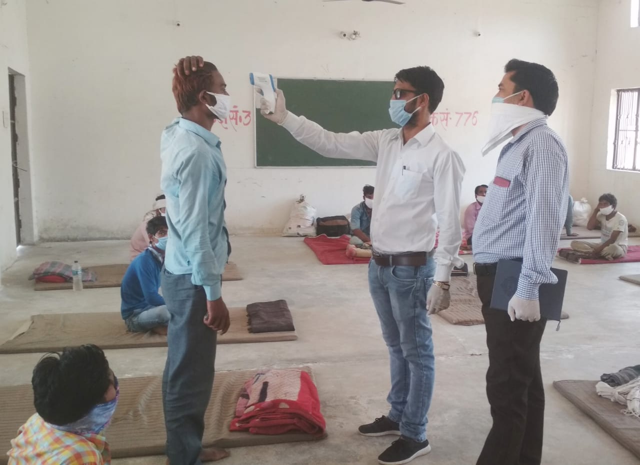 क्वारंटीन सेंटर में लोगों की थर्मल स्क्रीनिंग करते चिकित्सक
