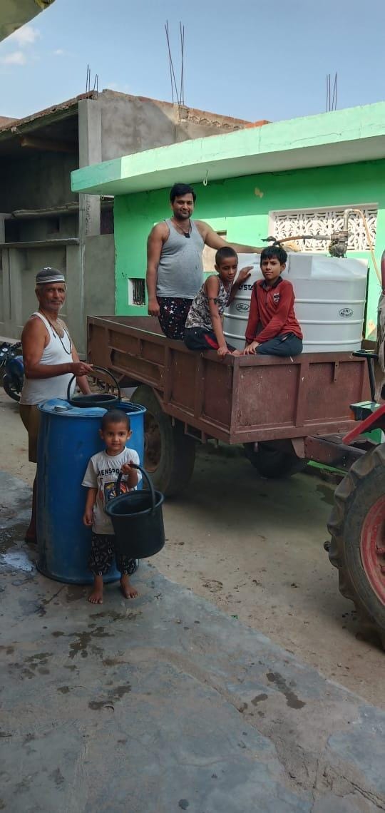 मुहम्मदाबाद में ट्रैक्टर पर लदी टंकी से पानी निकालते लोग मुहम्मदाबाद में ट्रैक्टर पर लदी टंकी से पानी निकालते लोग