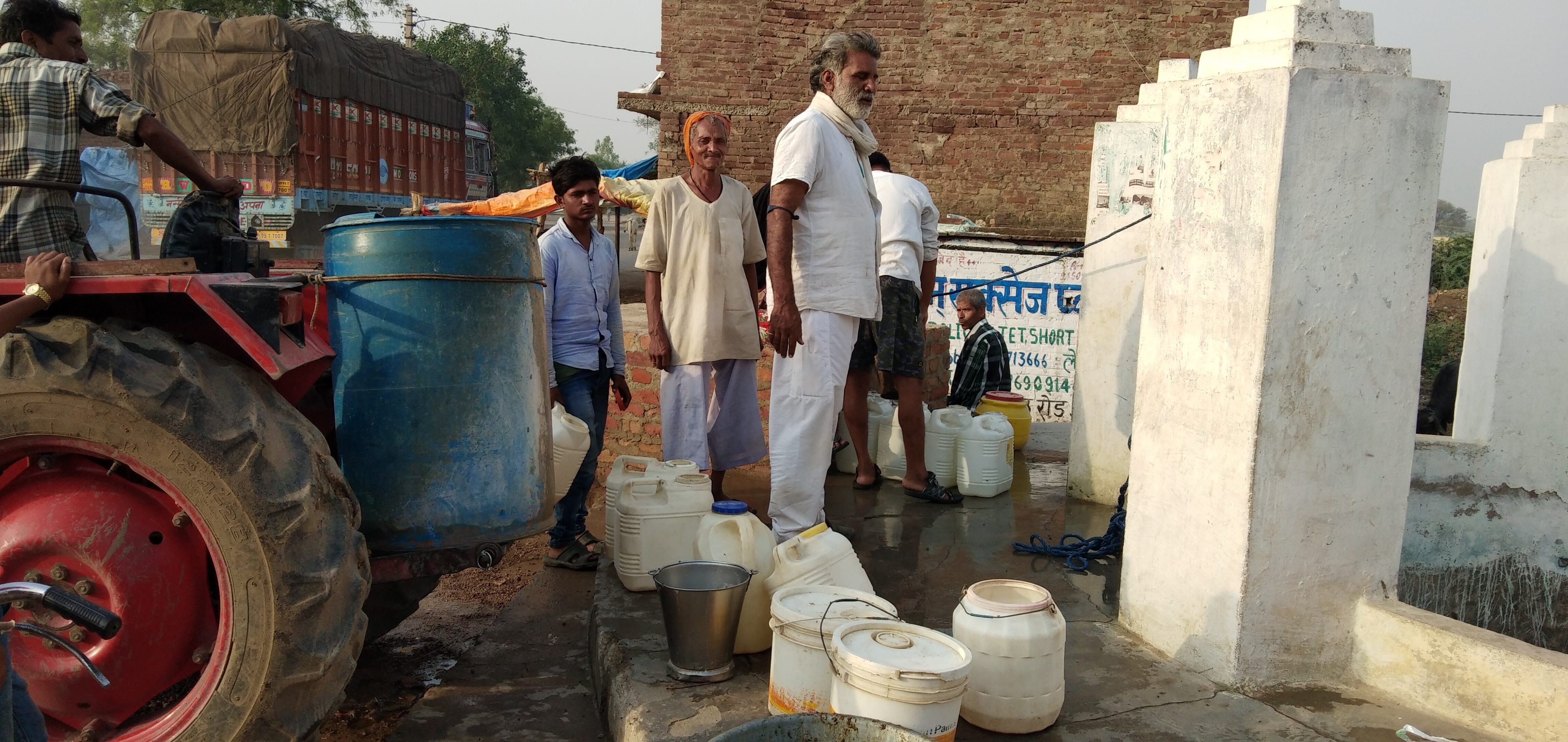 कुएं से पानी भरने के बाद ट्रैक्टर पर लादते लोग। कुएं से पानी भरने के बाद ट्रैक्टर पर लादते लोग।