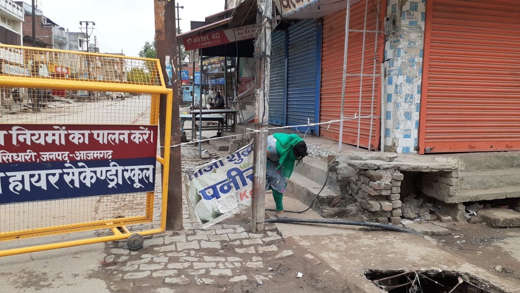 सिधारी में बने कंटेंमेंट जोन में बाड़ के नीचे से निकलती महिला। सिधारी में बने कंटेंमेंट जोन में बाड़ के नीचे से निकलती महिला।