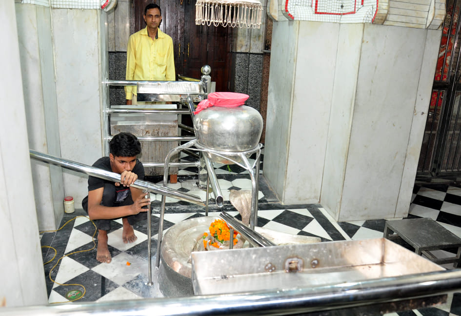 भूतेश्वर मन्दिर में जलाभिषेक के लिये पाईप लगाता कर्मी