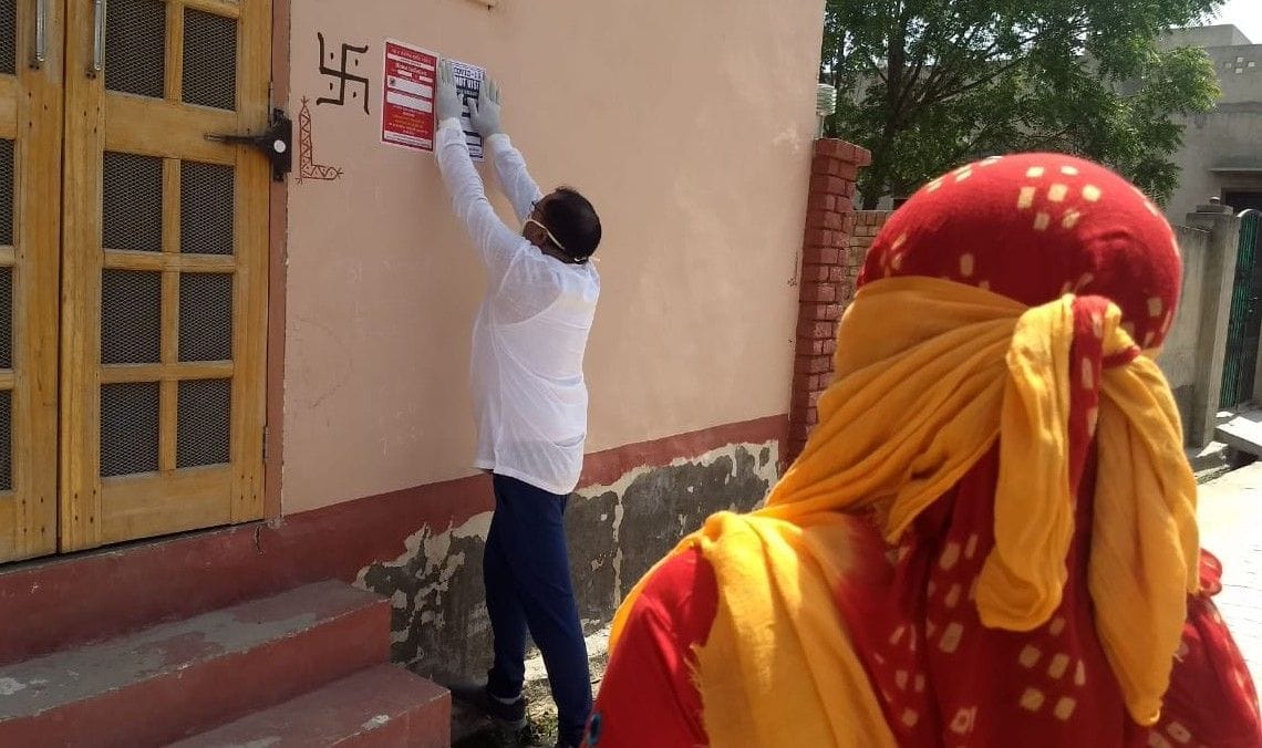 होम आइसोलेट किए गए कोरोना पॉजीटिव के घरों के बाहर पर्चा चस्पाते स्वास्थ्य कर्मी।