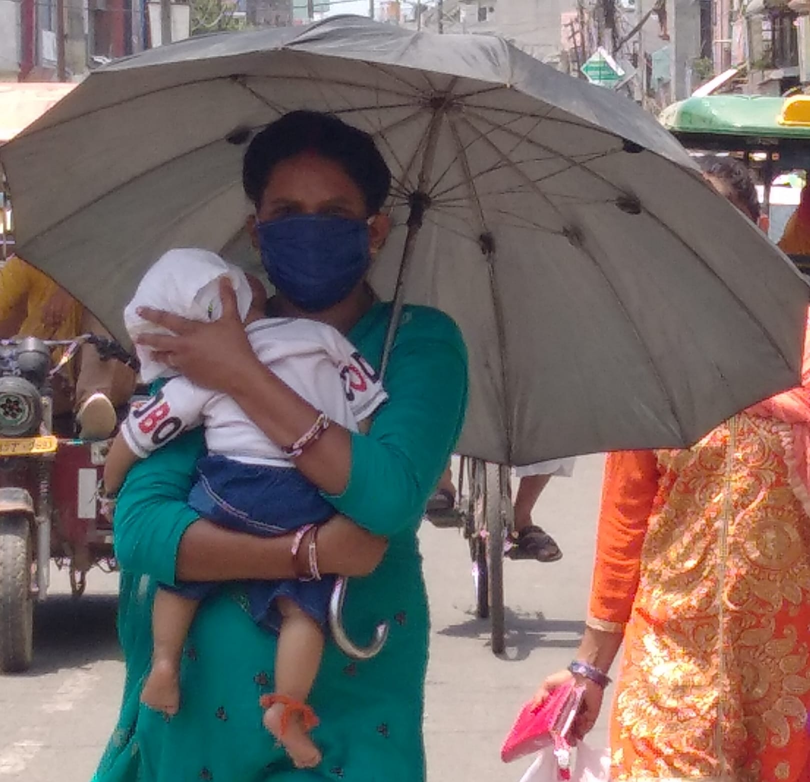 शामली गर्मी में छाता लगा कर बच्चे को गोद में लेकर गुजरती महिला शामली गर्मी में छाता लगा कर बच्चे को गोद में लेकर गुजरती महिला