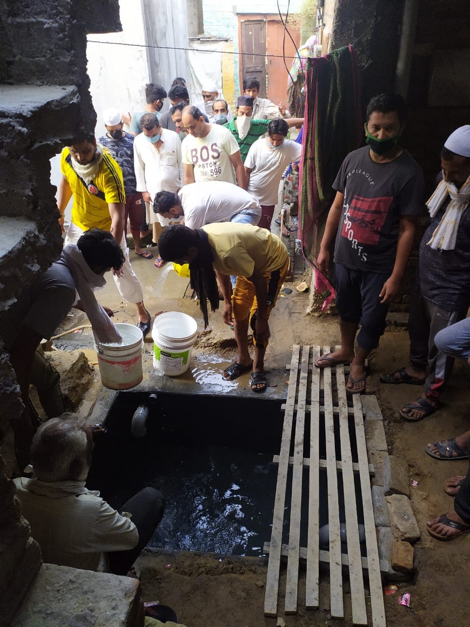 नकुड़ में शव को शौचालय के गढ्ढे से निकालने के लिए बाल्टियों से पानी बाहर निकालते लोग नकुड़ में शव को शौचालय के गढ्ढे से निकालने के लिए बाल्टियों से पानी बाहर निकालते लोग