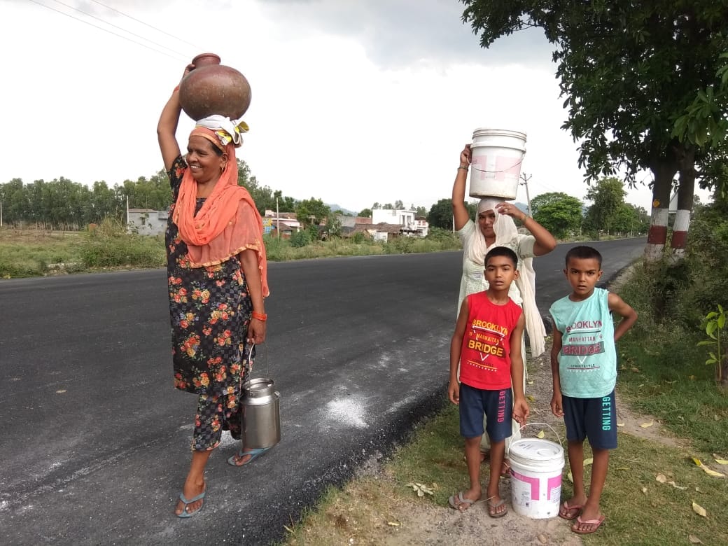 गणेशपुर में पेयजल आपूर्ति बाधित होने पर हैंडपंप से पानी सिर पर ढोती महिलाएं