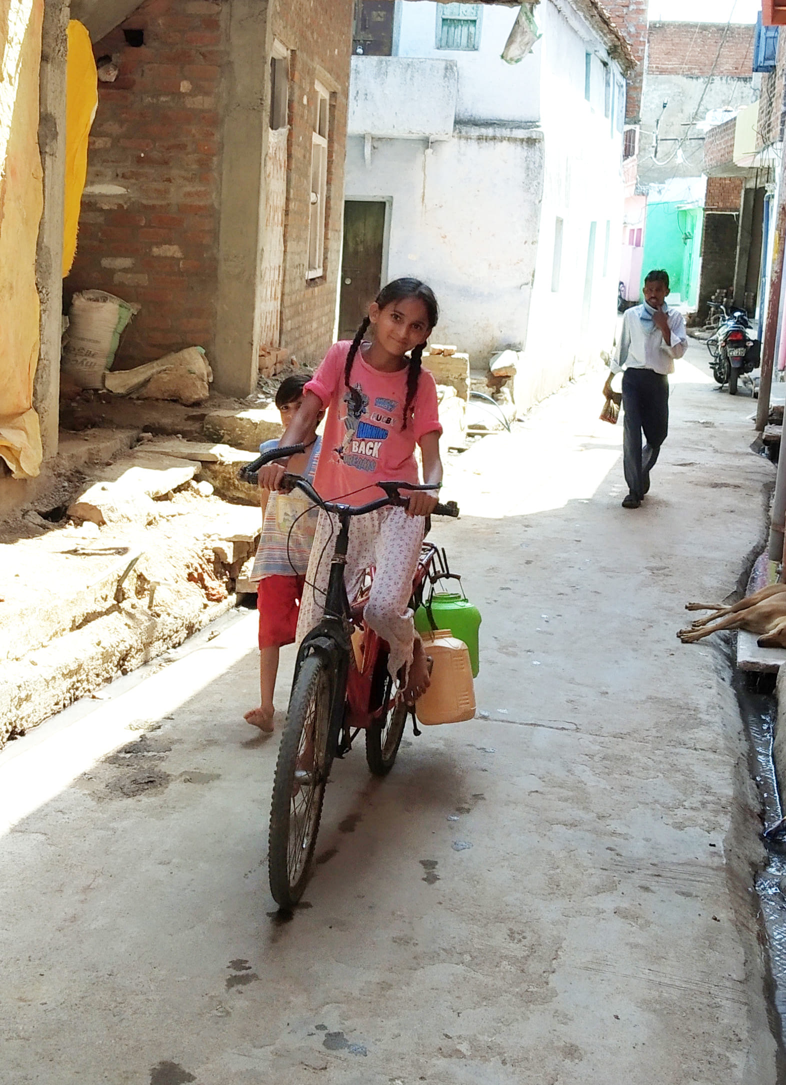 साइकिल से पानी ढोती बच्ची साइकिल से पानी ढोती बच्ची
