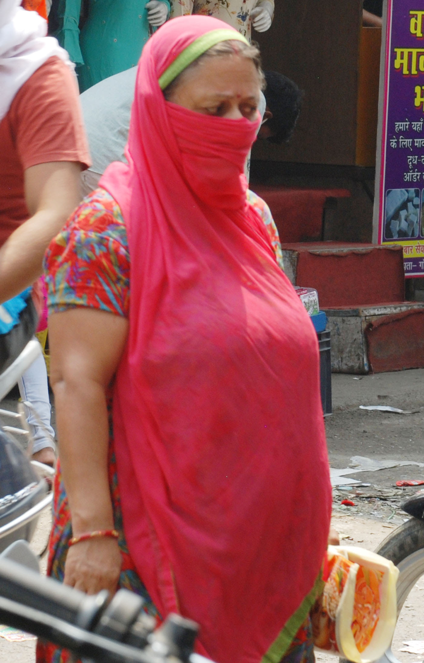 चेहरे पर कपड़ा लपेटकर गुजरती महिला