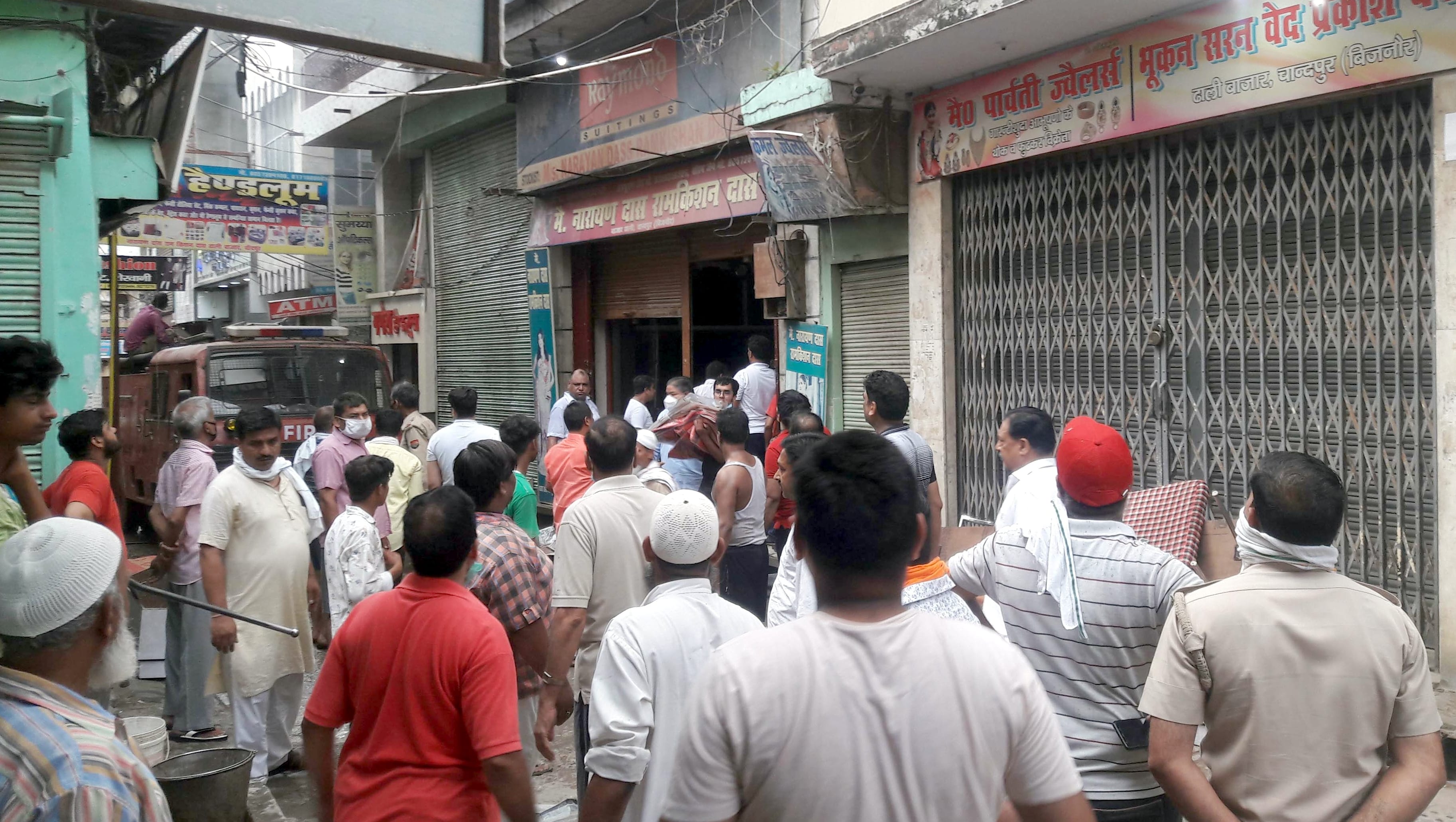 चांदपुर में कपड़े की दुकान में आग लगने के बाद जमा भीड़।