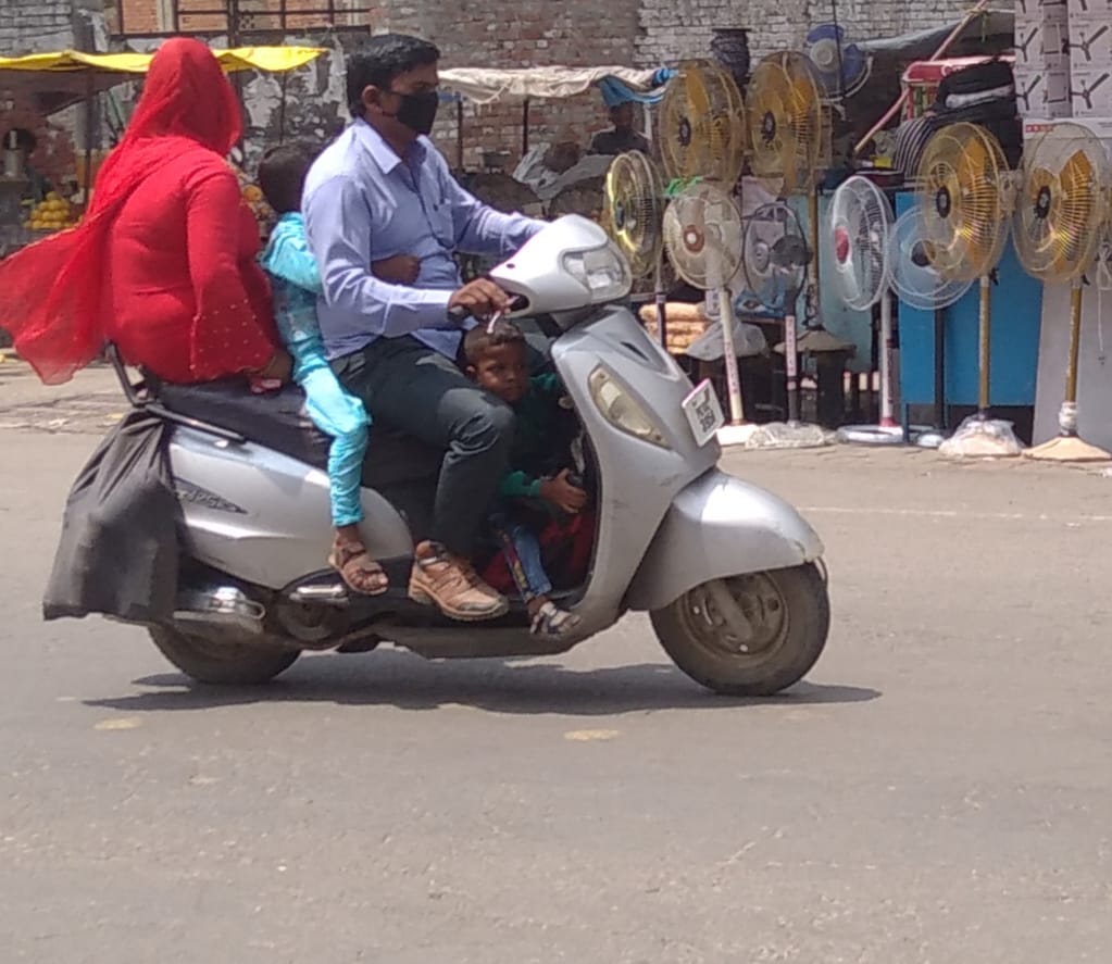 शामली फव्वारा चौक पर स्कूटी के बीच में बच्चे को बैठाकर ले जाता युवक शामली फव्वारा चौक पर स्कूटी के बीच में बच्चे को बैठाकर ले जाता युवक