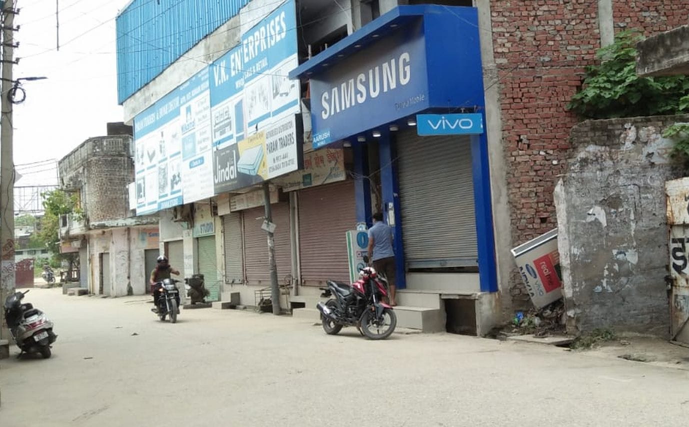 काशीपुर रोडवेज के सामने की गली में मोबाईल की दुकान का शटर बंद करता व्यक्ति।