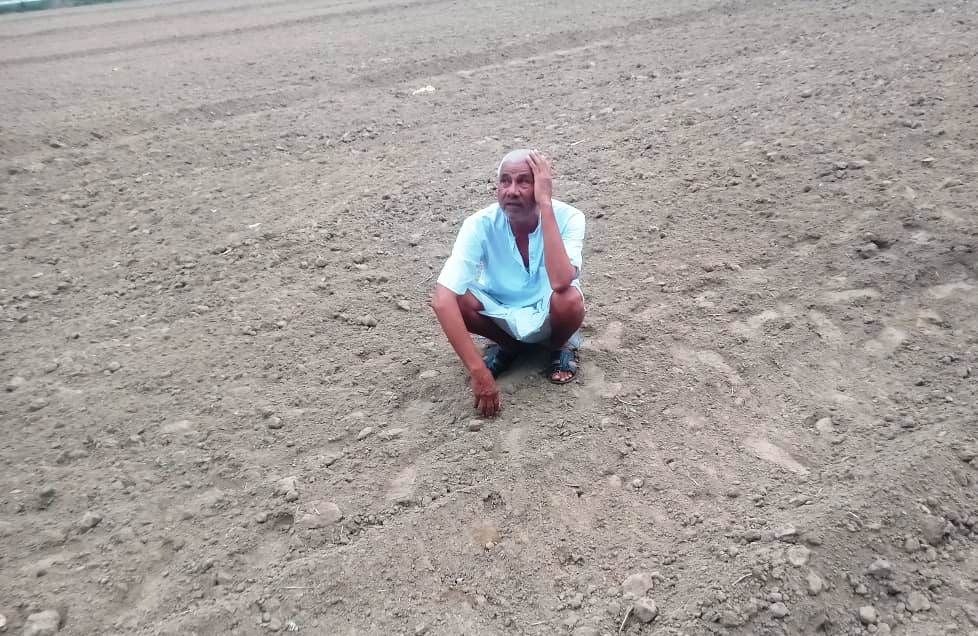 बारिश नहीं होने के कारण सूखी खेत में चिंता की मुद्रा में बैठे किसान। बारिश नहीं होने के कारण सूखी खेत में चिंता की मुद्रा में बैठे किसान।
