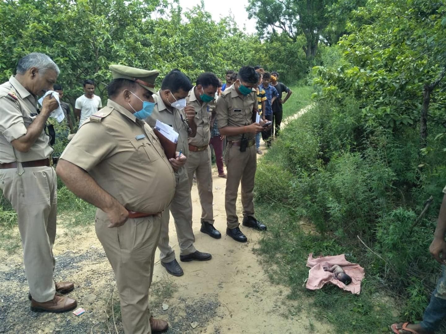 नवजात शिशु के शव को देखती पुलिस एवं भीड़