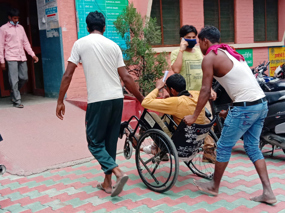 जिला अस्पताल में मरीज को व्हीलचेयर पर खींचकर ले जाते तीमारदार। जिला अस्पताल में मरीज को व्हीलचेयर पर खींचकर ले जाते तीमारदार।