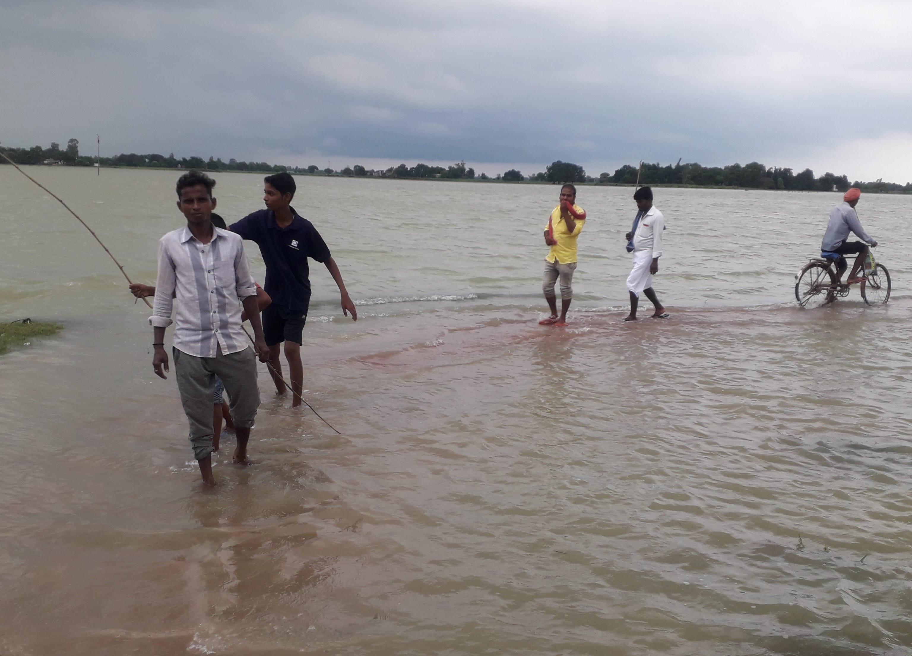 सगड़ी के भदौरा में बाढ़ के पानी से हो कर महुला गढ़वल बांध पर जाते ग्रामीण।