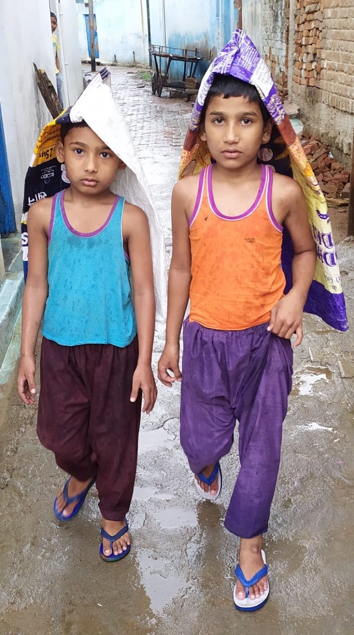 बोरी से सिर को ढककर बारिश से बचते बच्चे बोरी से सिर को ढककर बारिश से बचते बच्चे