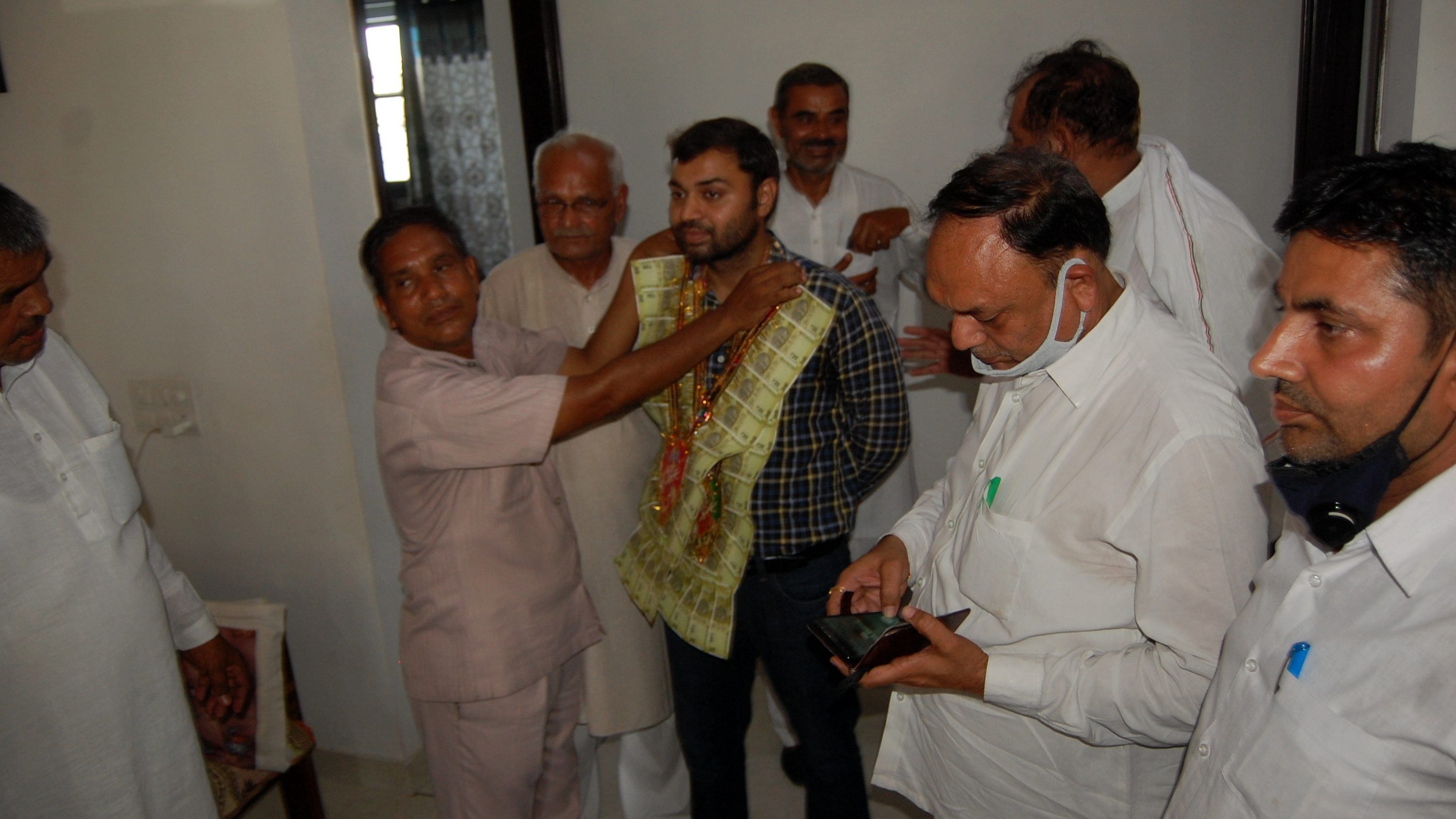 यूपीएससी में टॉपर बनने पर प्रदीप सिंह मलिक को नोटो की माला पहनाकर सम्मानित करते लोग।