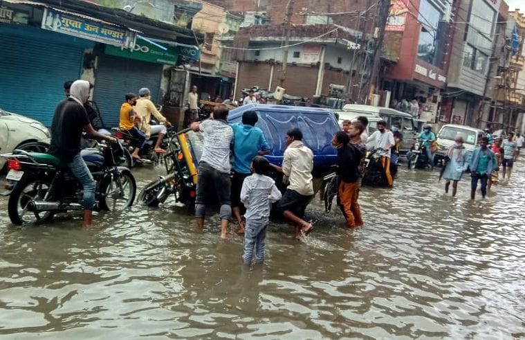फोटो-16- संडीला बाजार में बारिश के हुआ जलभराव व गड्ढे में फंसकर पलटे ई-रिक्शा को सीधा करते लोग। संवा?