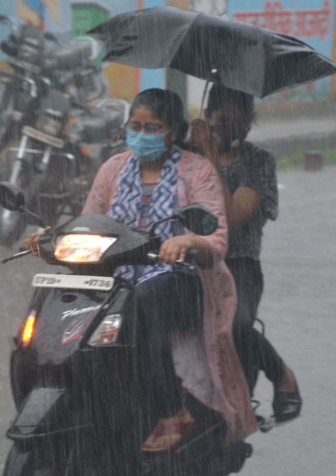 शामली बरसात में स्कूटी पर गुजरती महिला व युवती