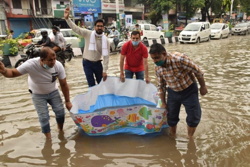 रुद्रपुर में अग्रेसन चौक पर नांव चलाकर जलभराव का विरोध करते व्यापारी।