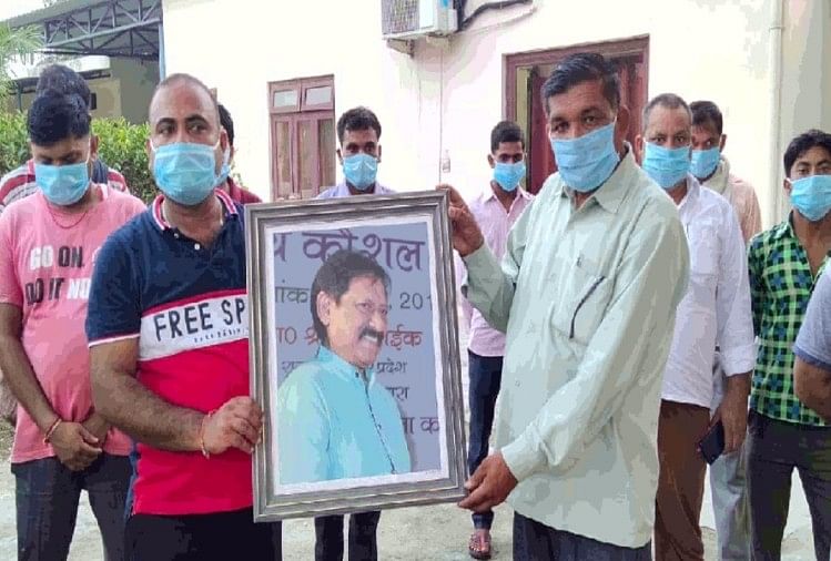 चौहन के चित्र के साथ फैक्टरी के शोकाकुल कर्मचारी