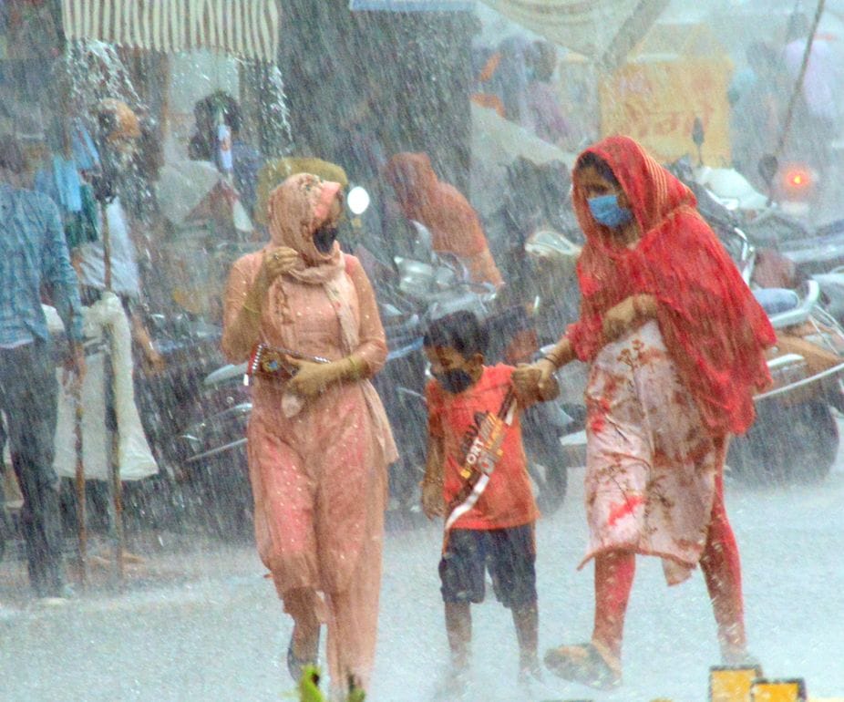 शहर में हुई झमाझम बारिश में गंतव्य को बच्चें के साथ जाती महिलाएं। शहर में हुई झमाझम बारिश में गंतव्य को बच्चें के साथ जाती महिलाएं।