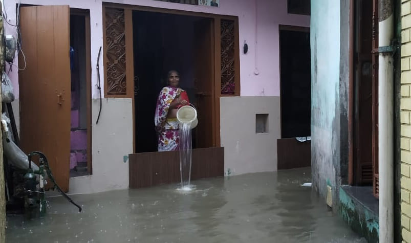 देवबंद में रविदास मार्ग स्थित जाटव नगर में घर में घुसे बारिश के पानी को बाहर निकालती महिला