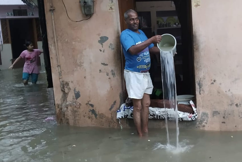 देवबंद बारिश के पानी को बाल्टी से बाहर निकालता व्यक्ति