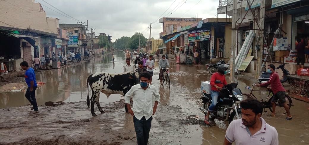 बीसवां मिल के पास स्टेट हाईवे पर पानी के बीच से गुजरते लोग बीसवां मिल के पास स्टेट हाईवे पर पानी के बीच से गुजरते लोग