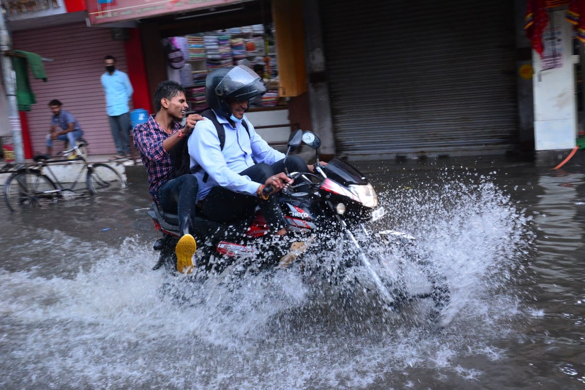 शहर में बारिश से हुए जलभराव से होकर गुजरता बाइक सवार। शहर में बारिश से हुए जलभराव से होकर गुजरता बाइक सवार।