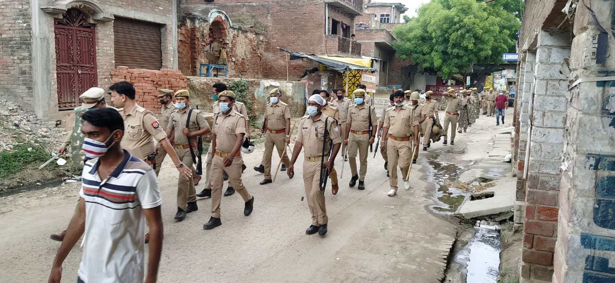 बिल्हौर (कानपुर) के मकनपुर-इलियासपुर गांव में पैदल मार्च करते पुलिस-पीएसी के जबान व अधिकारी