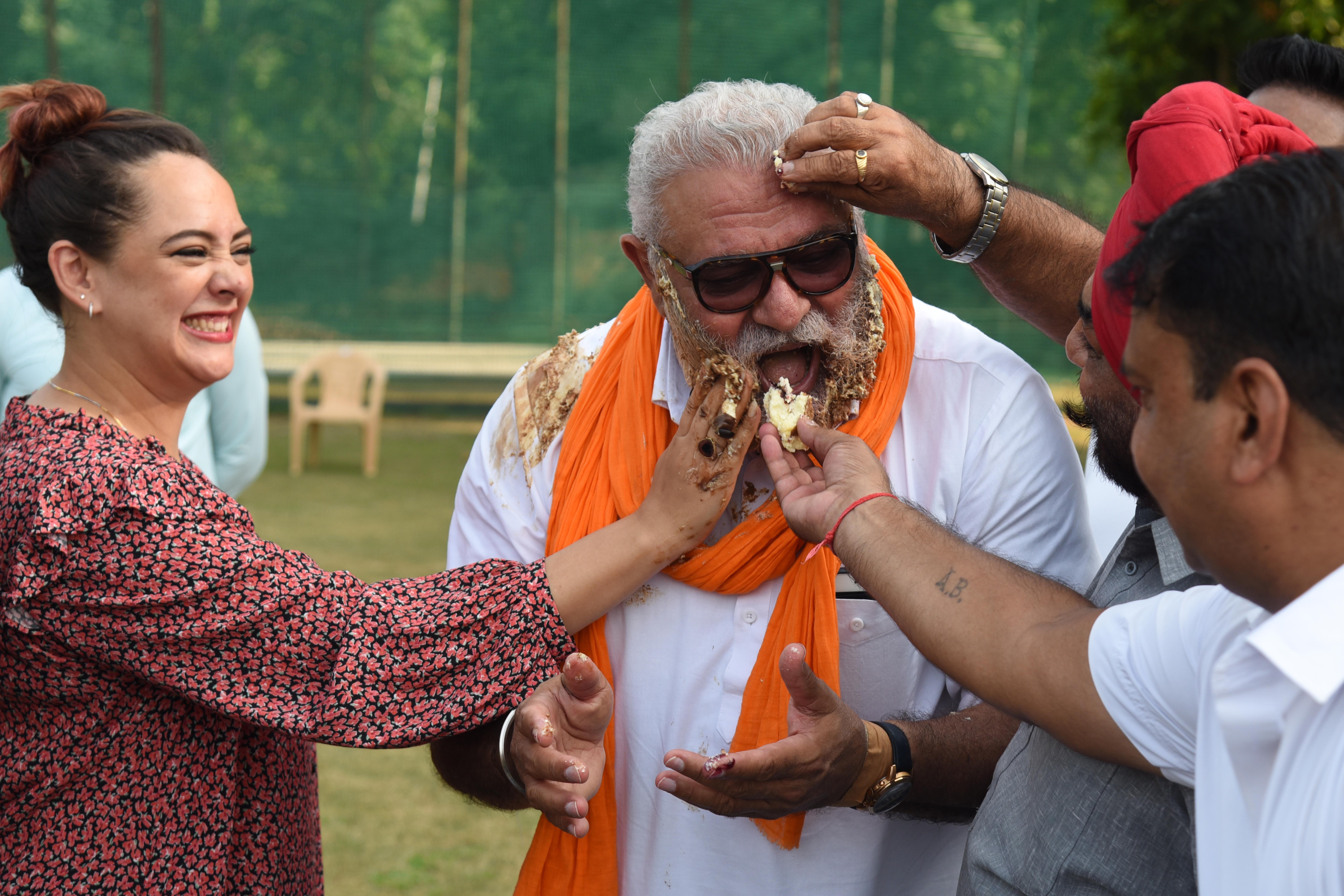समारोह के दौरान योगराज को केक खिलाते अन्य लोग। 