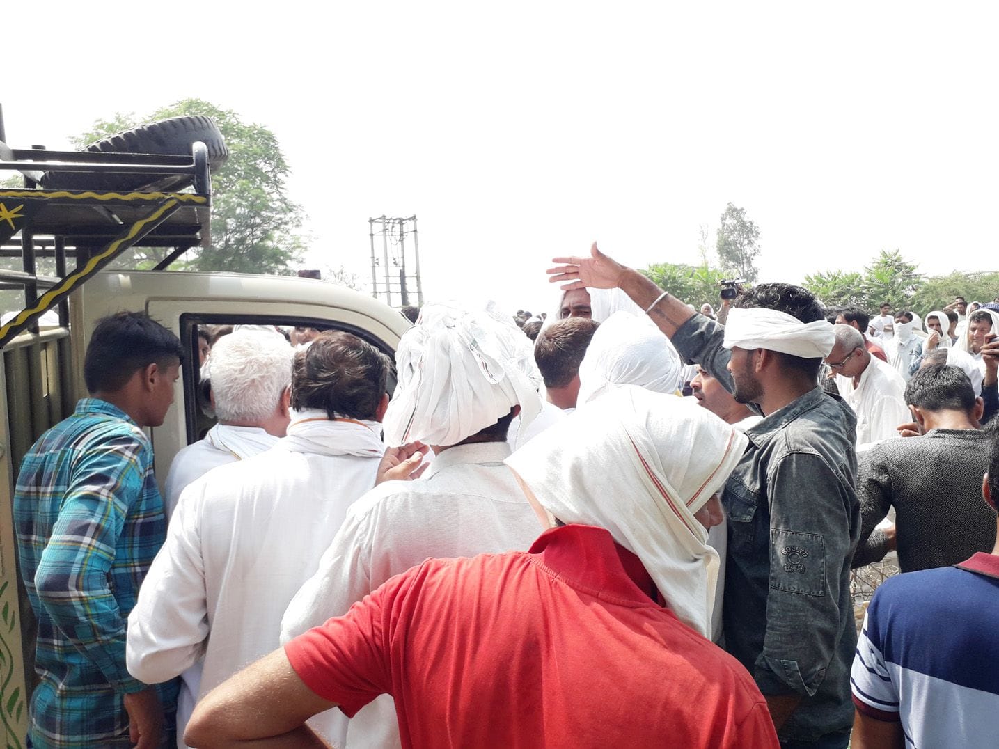  रोड जाम के दौरान धरने के बीच से गाड़ी निकालने की कोशिश कर रहे चालक से बहस करते लोग।