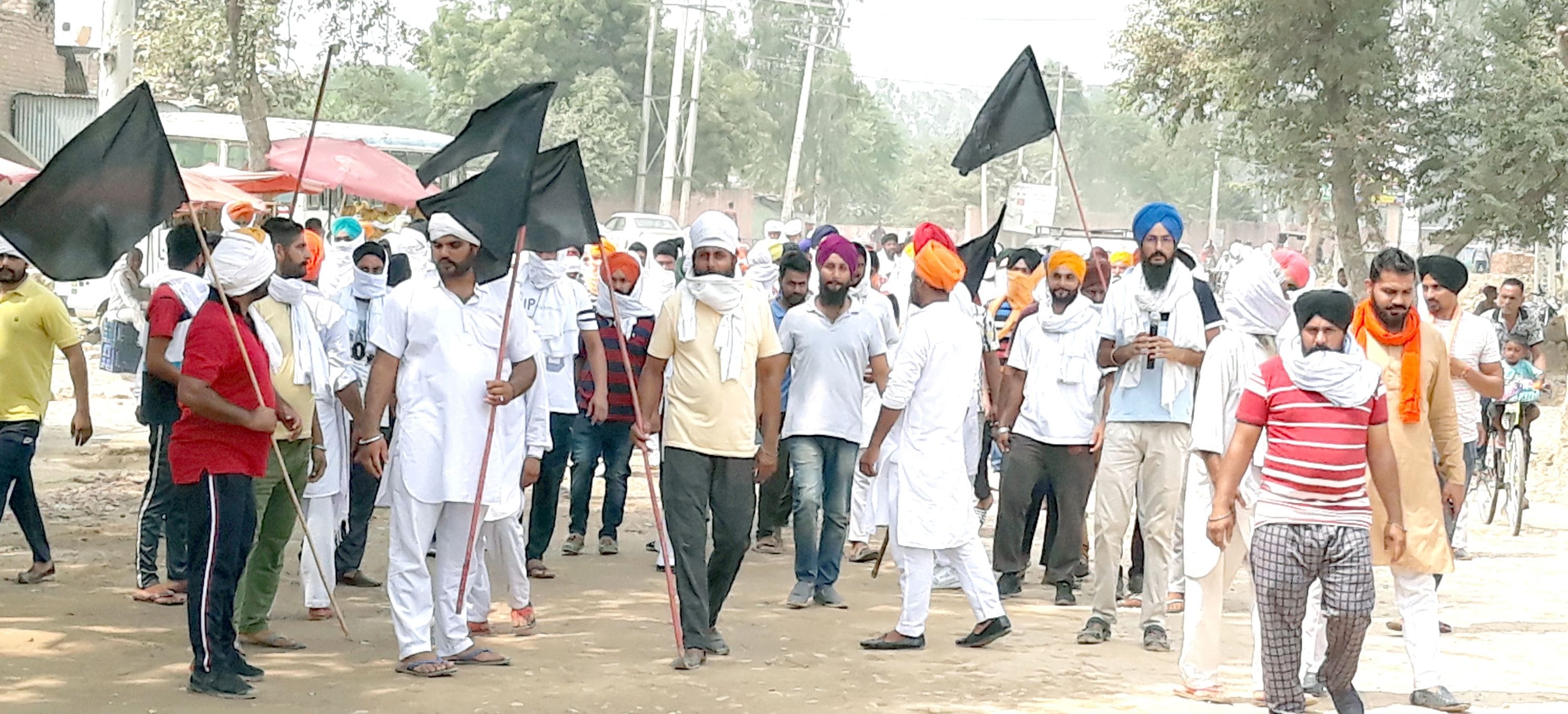   काले झंडे लेकर धरनास्थल की तरफ जाते किसान।