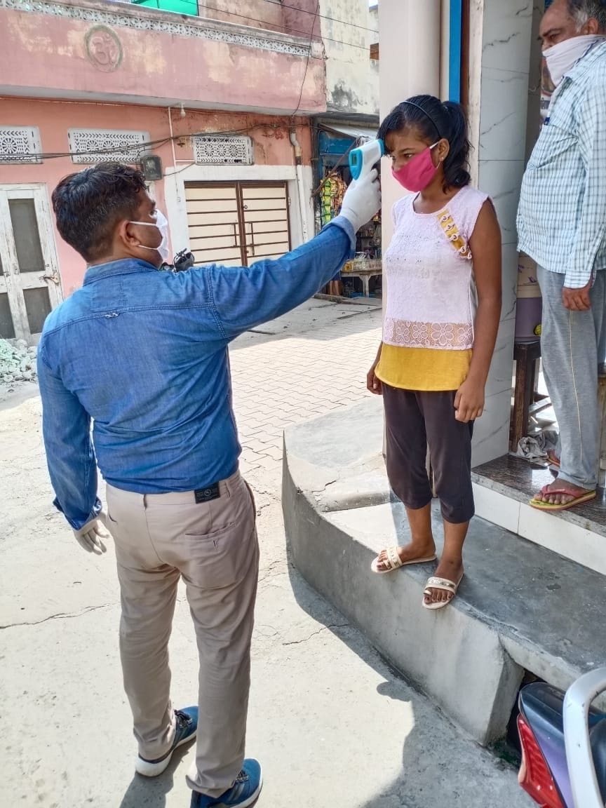 लड़की की थर्मल स्क्रीनिंग करता स्वास्थ्य कर्मचारी। लड़की की थर्मल स्क्रीनिंग करता स्वास्थ्य कर्मचारी।