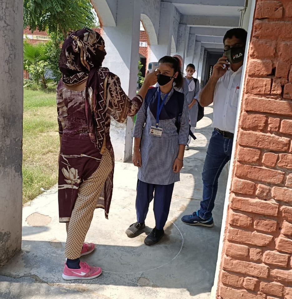 स्कूल में दाखिल होने से पहले बच्चों की थर्मल स्कैनिंग करते हुए।