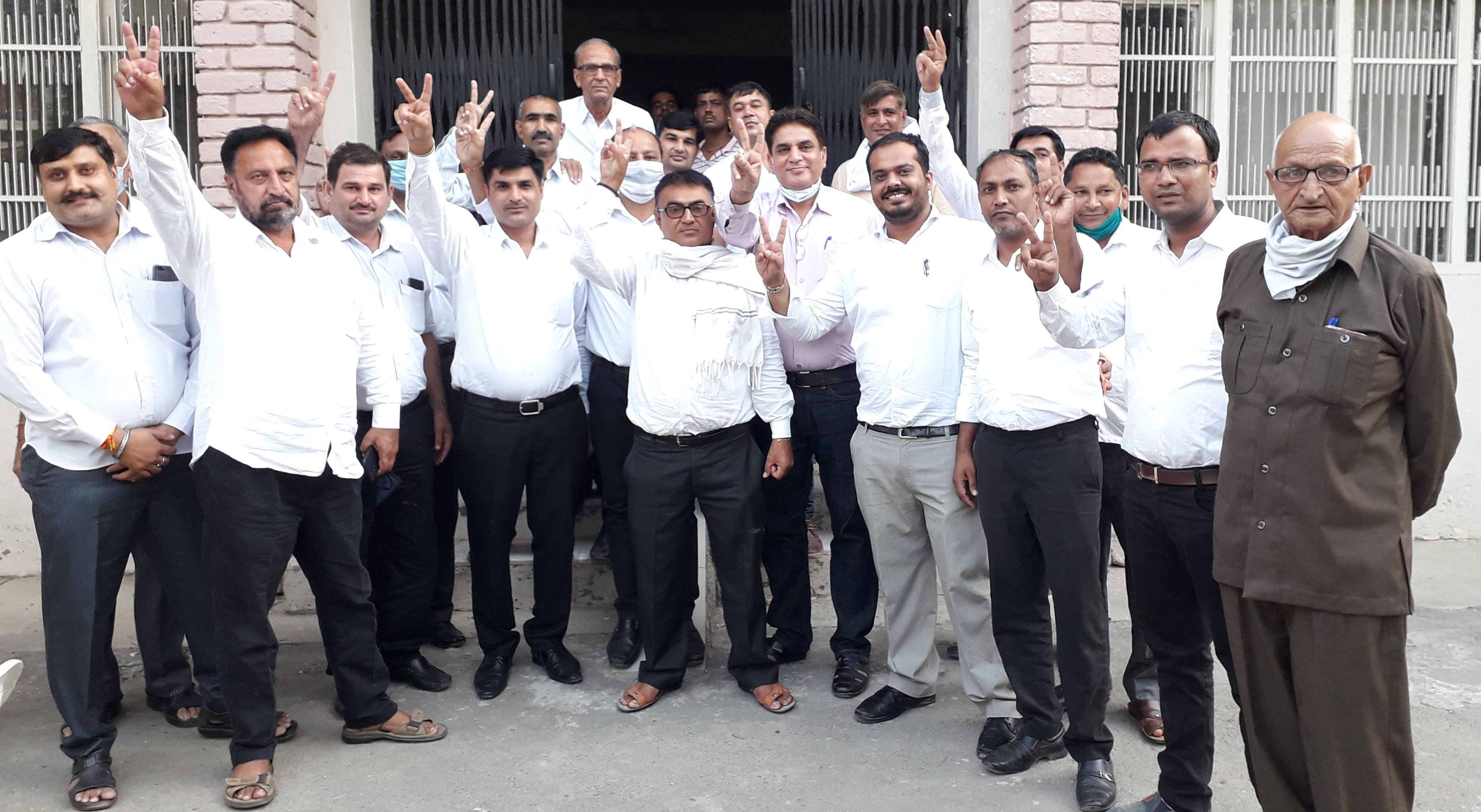  प्रधान रमेश भारद्वाज के साथ विजय चिह्न बनाते वकील।