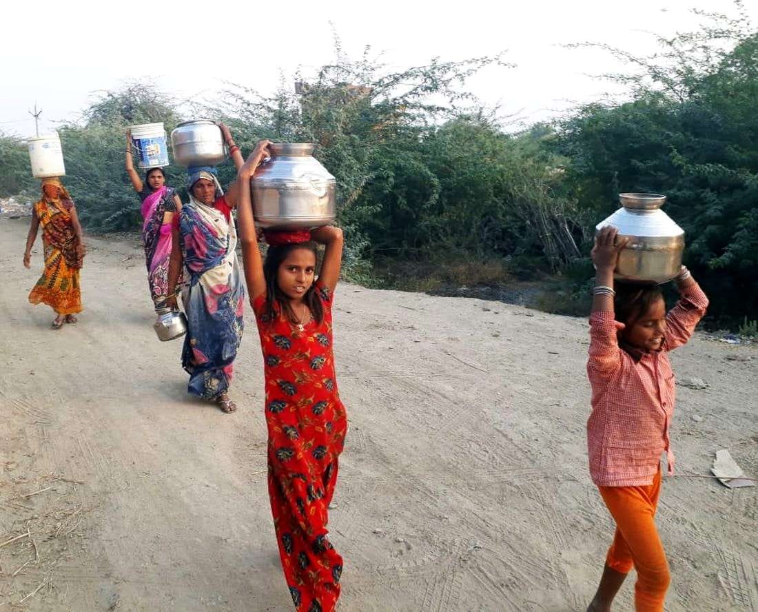 कोसों दूर से सिर में बर्तन रखकर पानी लातीं महिलाएं