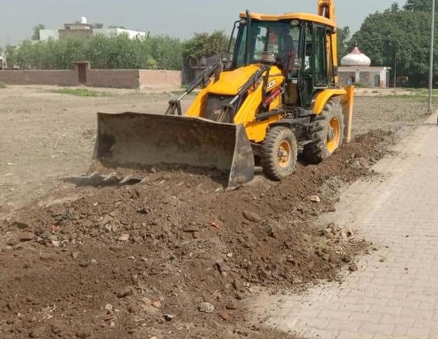 बीसलपुर के मोहल्ला दुबे के भूखंड की खोदी गई नींव को समतल करती जेसीबी।