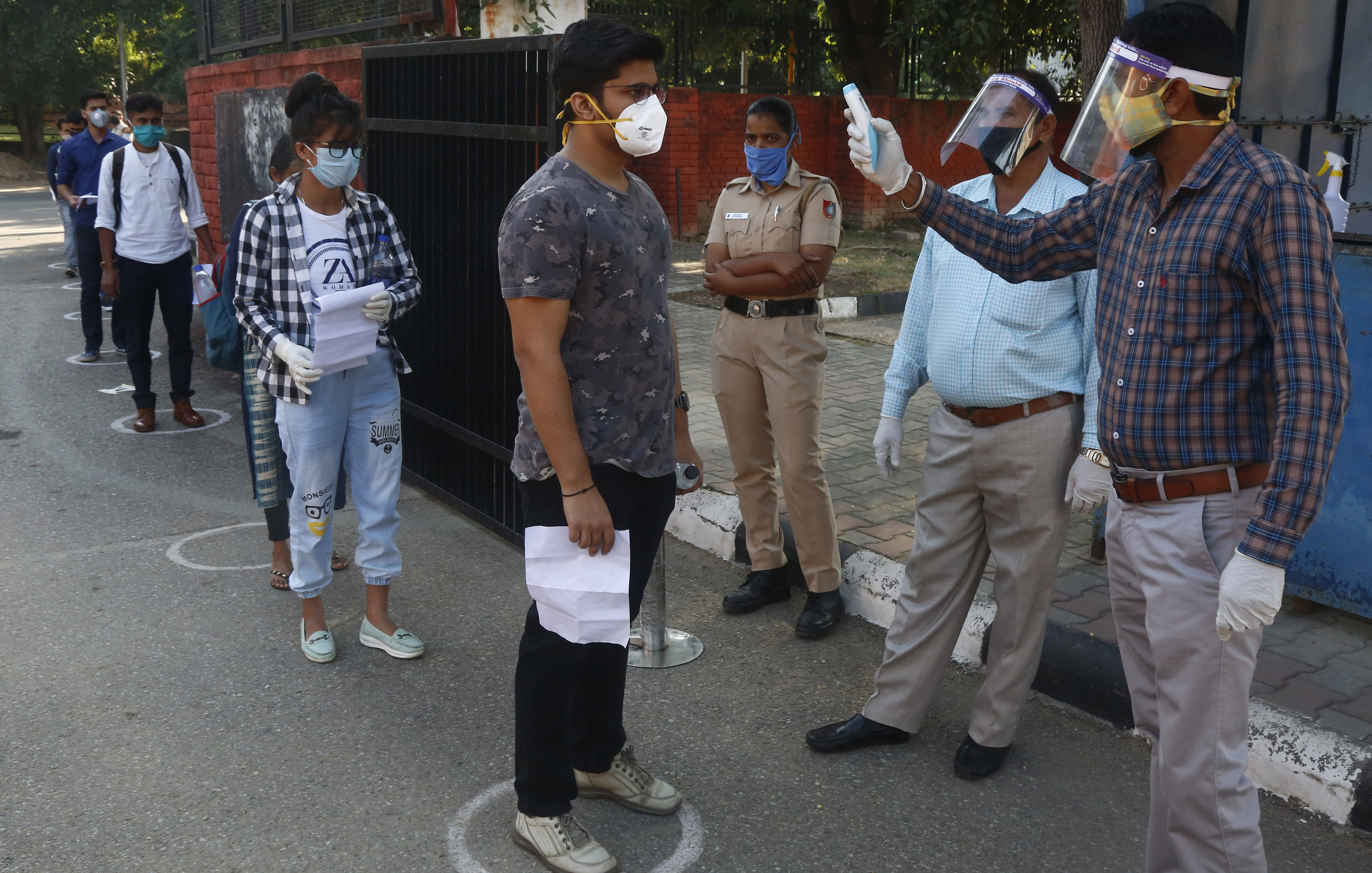 परीक्षार्थियों का तापमान चेक करते कर्मचारी। 